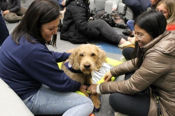 2 people smiling and petting dog